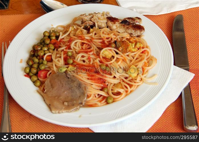 Dish in restaurant vermicelli meat peas sauce with fork and knife. Spaghetti with meat vegetables and sauce. Cooked pasta with beef and peas on plate. Dish in restaurant vermicelli meat peas sauce with fork and knife