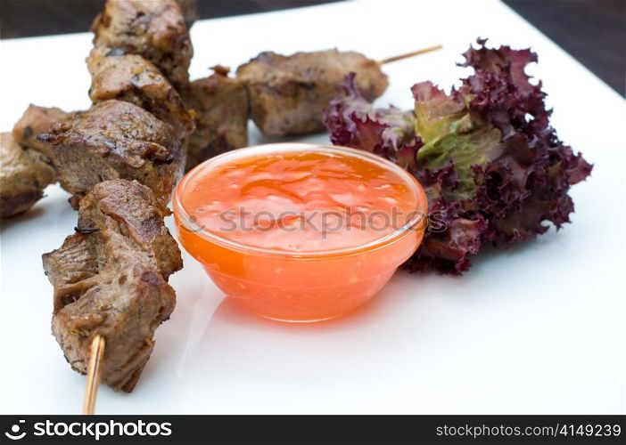 dish of fresh kebabs on sticks with hot sauce, copy space. kebabs on sticks with hot sauce