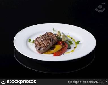 dish of fried meat in a plate on a black background. dish on black background