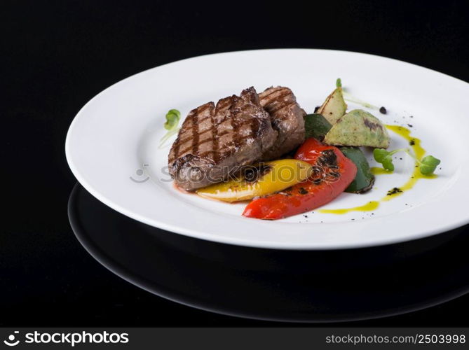 dish of fried meat in a plate on a black background. dish on black background