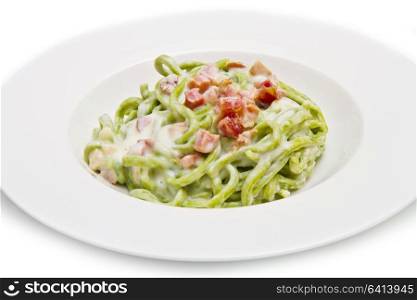 dish of green spaghetti with bacon and cream