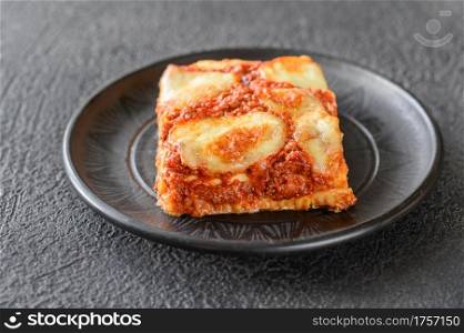 Dish of lasagne on black background