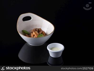 dish of meat in a bowl on a black background, isolated. dish on black background