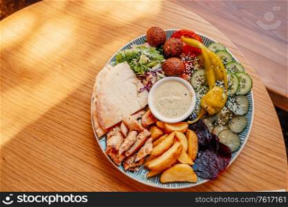 Dish of palestinian or israeli food - falafel, pita and vegetables with souse, shot with copyspace.. Dish of palestinian or israeli food - falafel, pita and vegetables