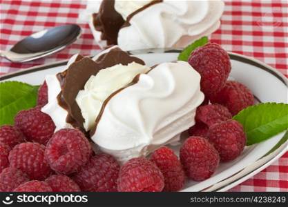 Dish of raspberries with chocolate meringues on a red gingham tablecloth