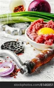 Dish of raw minced beef meat and parts of meat grinder. Raw minced beef