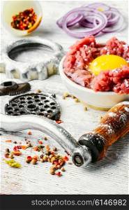 Dish of raw minced beef meat and parts of meat grinder. Raw minced beef
