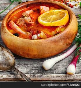 Dish of Russian cuisine-beef stew. Traditional Solyanka with smoked meats in wooden plate