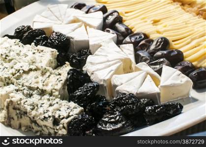 Dish with different types of cheese and olives as appetizer closeup
