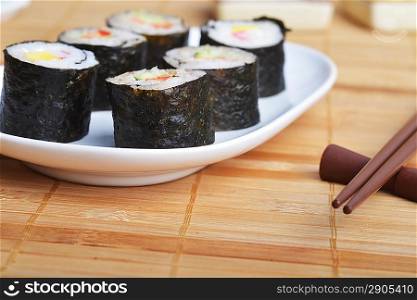 dish with fresh sushi rolls on bamboo napkin background