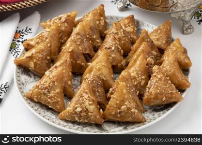 Dish with fresh traditional Almond briouats, coated in warm honey and filled with almond paste flavored with cinnamon and orange flower water close up