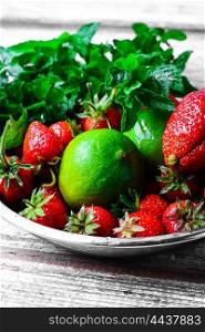 Dish with ripe large strawberries,lime and peppermint leaves
