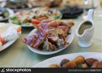 Dish with roasted young pig. Food table background.