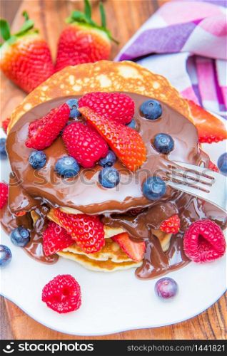 dish with stack of pancakes with choclate and berries
