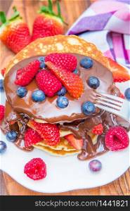 dish with stack of pancakes with choclate and berries