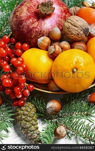 dish with tangerines,pomegranates,persimmons and nuts,decorated with fir branches