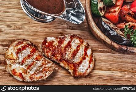 dishes of roast meat. Pork steak with vegetables and sauce on a old wooden table