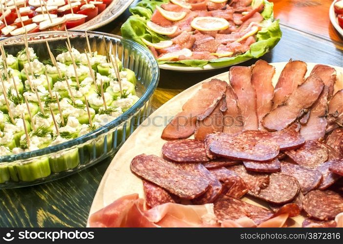 Dishes with sliced sausages and vegetarian cocktail bites as appetizer closeup