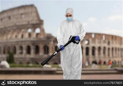 disinfection and pandemic concept - sanitation worker in protective gear or hazmat suit, medical mask, gloves and goggles with pressure washer or sanitizer over coliseum in rome, italy on background. sanitation worker in hazmat with pressure washer