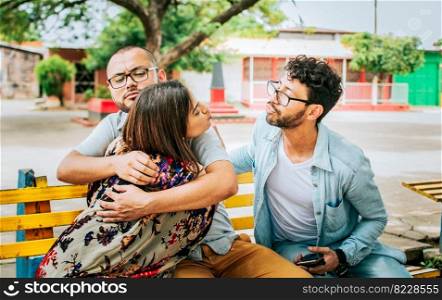 Disloyal girlfriend hugging her boyfriend in a park secretly kissing another man. Couple infidelity concept, Unfaithful woman sitting hugging her boyfriend and secretly kissing another man.