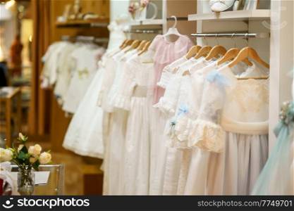 Display rack with first communion dresses for girls in a luxury children&rsquo;s clothing shop. Children&rsquo;s party dresses shop.. Display rack with first communion dresses for girls in a luxury children&rsquo;s clothing shop.