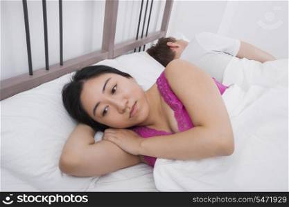 Displeased woman with man sleeping in bed