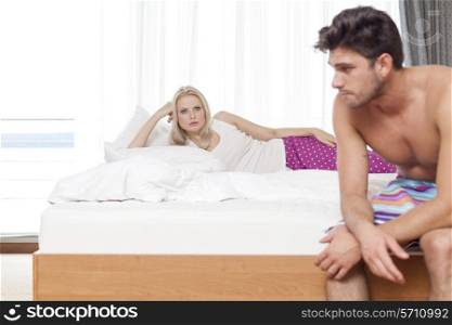 Displeased young couple on bed in hotel room