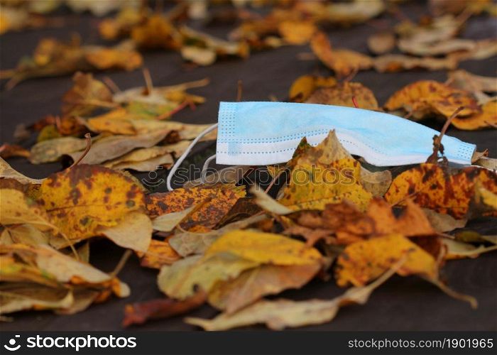 Disposable face mask lying on the street around leaves in autumn during Covid19 pandemic .. Disposable face mask lying on the street around leaves in autumn during Covid19 pandemic