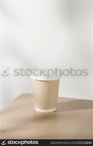 Disposable paper coffee cup on a wooden table at cafe.