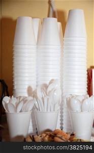 Disposable plastic kitchen utensils pile stack cups and spoons on table