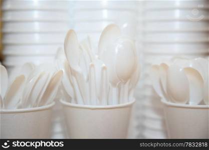 Disposable plastic kitchen utensils pile stack cups and spoons on table
