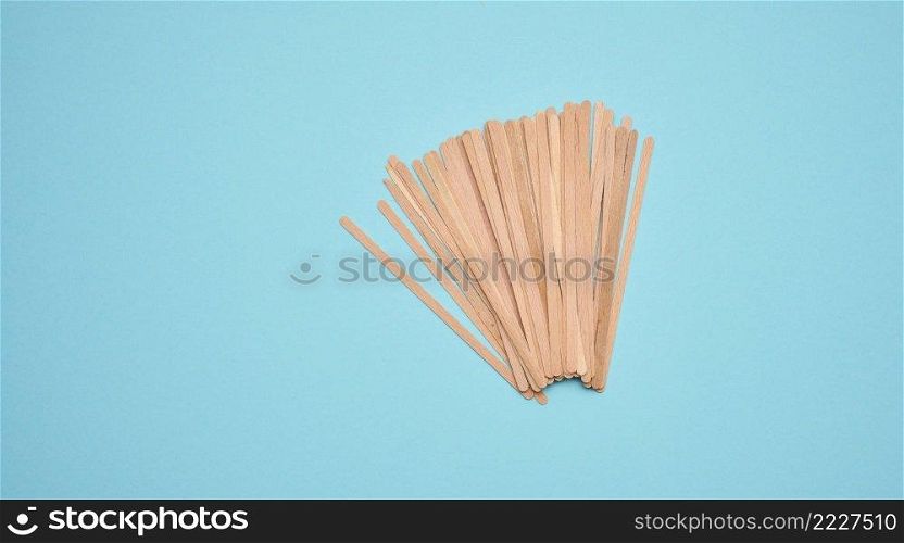 disposable wooden sticks for stirring hot drinks on a blue background. Coffee and tea spoon, zero waste