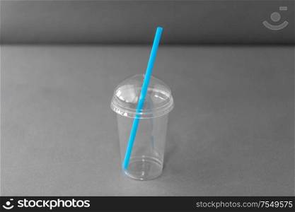 dispose, recycling and ecology concept - transparent takeaway plastic cup with straw on grey background. white disposable plastic cup with spoon