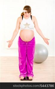Dissatisfied with her weight pregnant woman standing on weight scale at home&#xA;