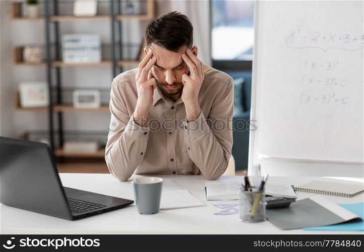 distance education, remote job and stress concept - tired male teacher with laptop computer having headache at home office. tired male teacher having headache at home