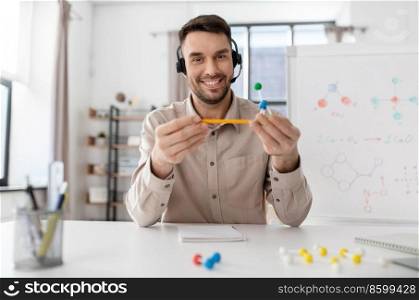 distance education, school and remote job concept - happy smiling male chemistry teacher in headset with molecular model having online class at home office. chemistry teacher in headset having online class