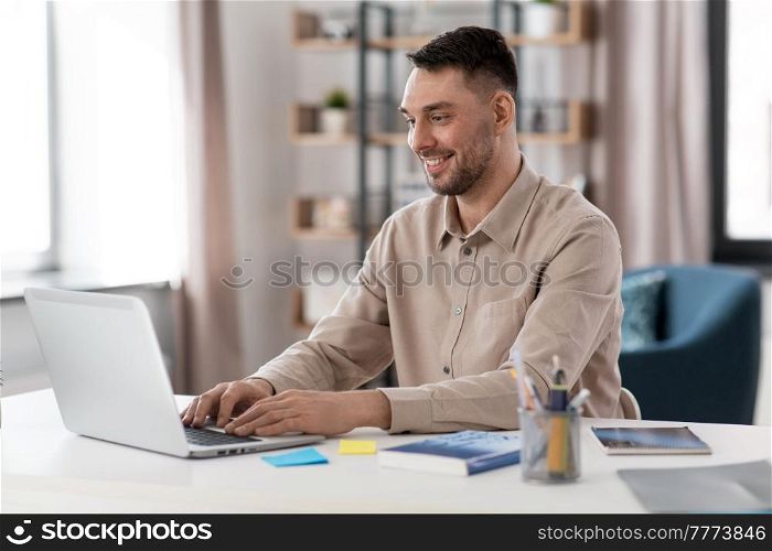 distance education, school and remote job concept - happy smiling male teacher or student with laptop working or learning at home office. smiling male teacher with laptop working at home