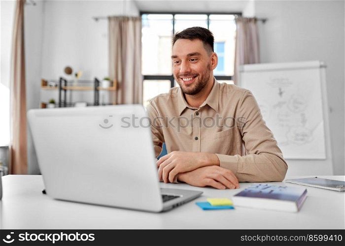 distance education, school and remote job concept - happy smiling male teacher with laptop working at home office. smiling male teacher with laptop working at home
