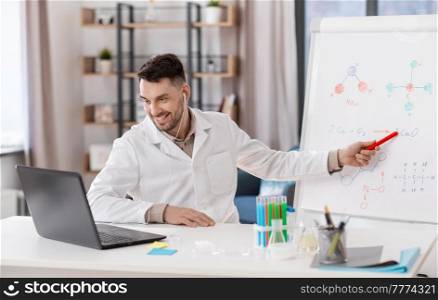 distance education, school and science concept - happy smiling male chemistry teacher in earphones with laptop computer having online class and showing molecular model on flip chart at home office. chemistry teacher with laptop having online class