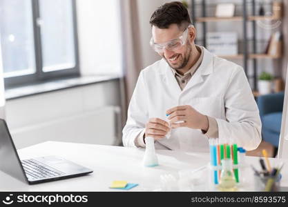 distance education, school and science concept - happy smiling male chemistry teacher in goggles and earphones with laptop computer and test tube with chemical having online class at home office. chemistry teacher with laptop having online class