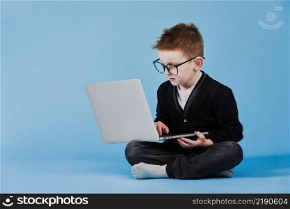 Distance learning online education. Schoolboy studying at home with laptop and doing school homework on blue background.. Distance learning online education. Schoolboy studying at home with laptop and doing school homework on blue background