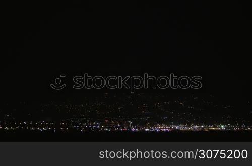Distant city lights and lightning discharges in dark sky. Night thunderstorm