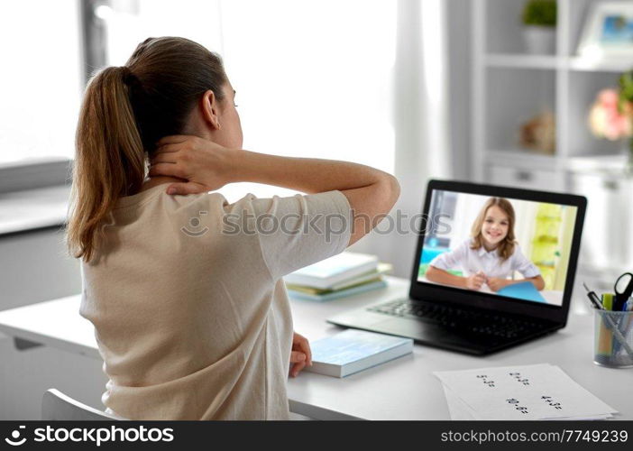 distant education, remote job and health concept - tired female teacher having video call or online class with student girl on laptop computer screen and touching her neck at home office. tired teacher with laptop touching neck at home