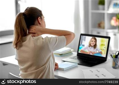 distant education, remote job and health concept - tired female teacher having video call or online class with student girl on laptop computer screen and touching her neck at home office. tired teacher with laptop touching neck at home