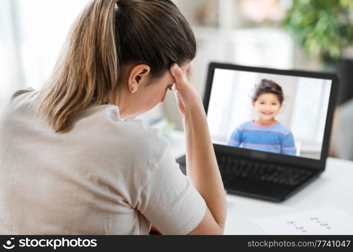distant education, remote job and health concept - tired female teacher with little student girl laptop computer having headache at home office. tired teacher with laptop having headache at home