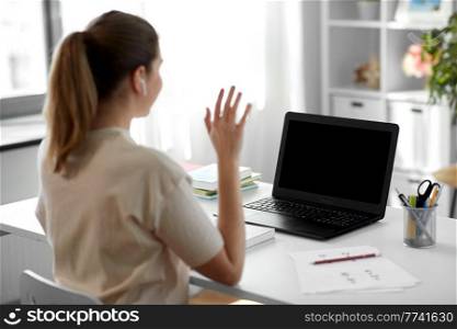 distant education, remote job and people concept - happy smiling female teacher with laptop computer having video call or online class at home office. teacher with laptop having video call at home