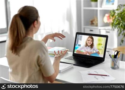 distant education, remote job and people concept - happy smiling female teacher with student girl on laptop computer screen having video call or online class at home office. teacher with laptop having video call at home