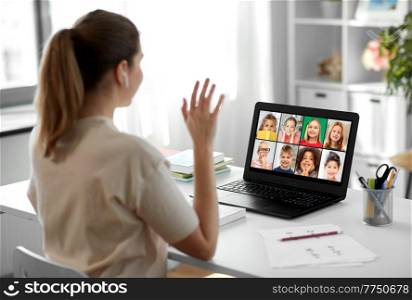 distant education, remote job and people concept - happy smiling female teacher with children on laptop computer screen having video call or online class at home office. teacher with laptop having online class at home