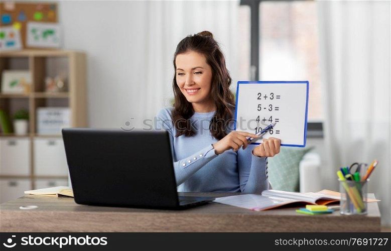 distant education, school and people concept - happy smiling female math teacher with laptop computer and mathematics having online class at home. math teacher having online class at home