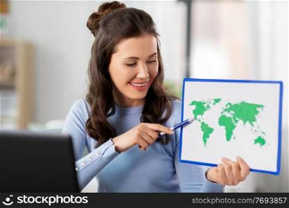distant education, school and people concept - happy smiling female teacher with world map and laptop computer having online geography class at home. teacher with world map having online class at home